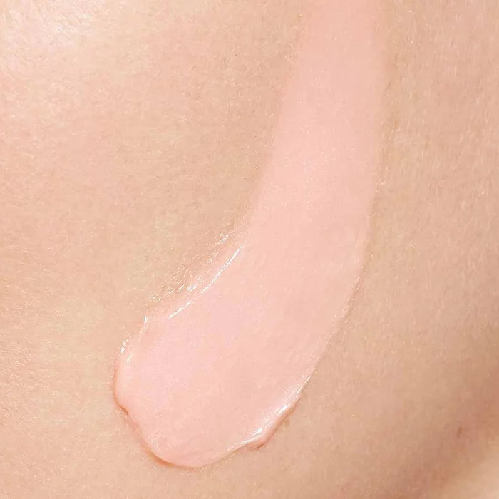 Rosa Creme wird auf eine Gesichtshaut aufgetragen, was eine Nahaufnahme des Hautpflegerituals zeigt.
