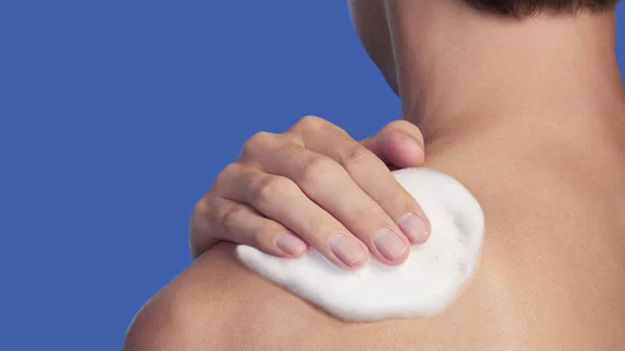 un homme appliquant du gel douche sur son epaule